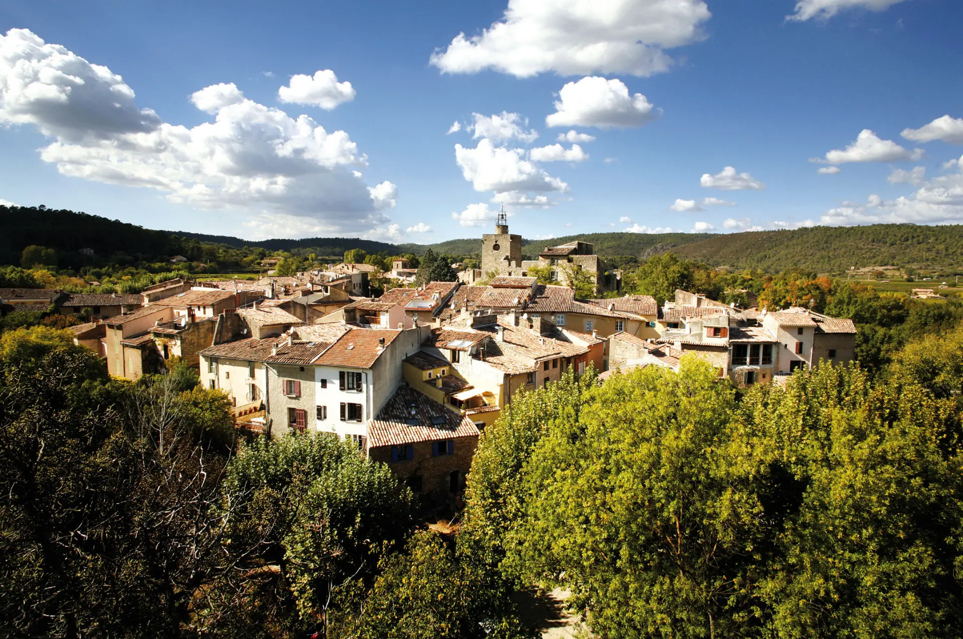 Village de Correns avec toits en tuiles, église et collines verdoyantes