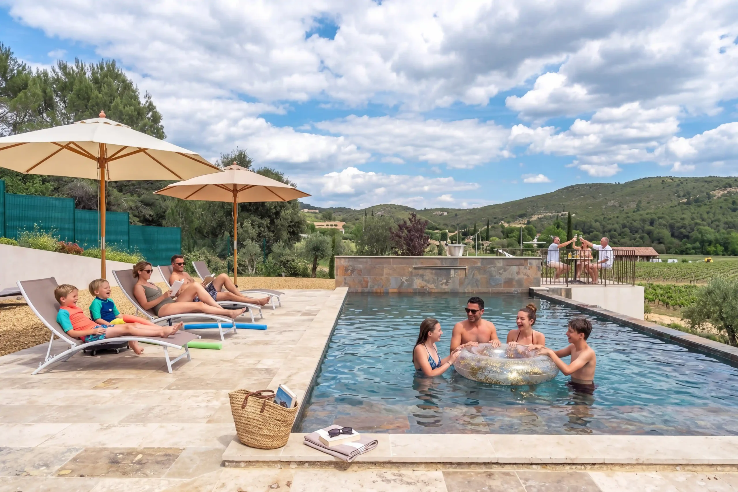 Famille profitant de la piscine avec bouée, transats et parasols en Provence