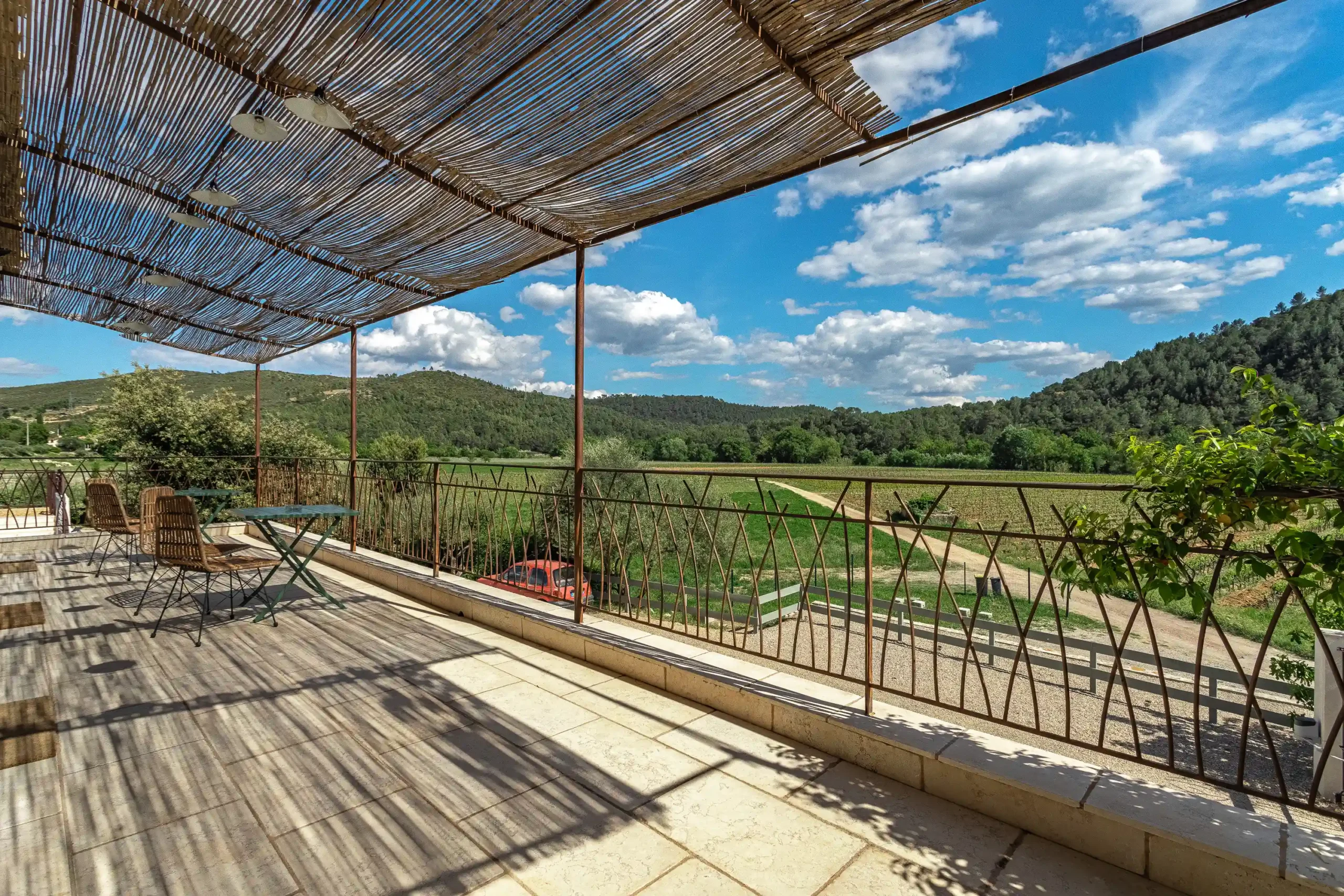 Terrasse couverte avec toit en canisses offrant une vue sur les collines verdoyantes