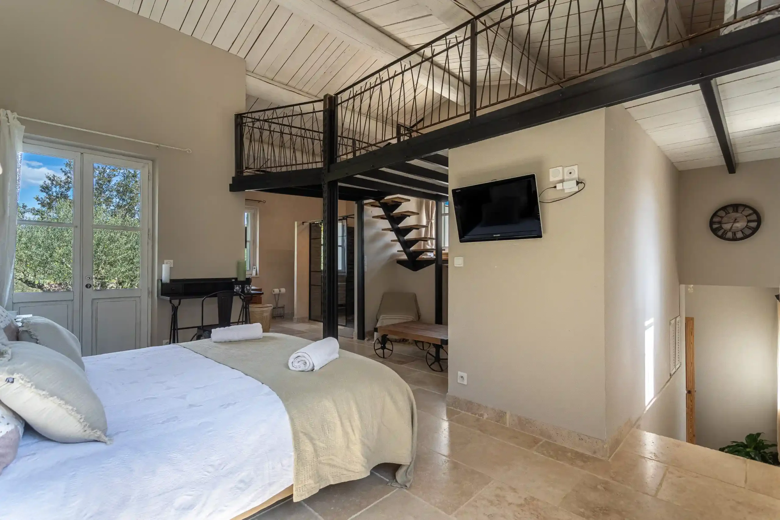 Chambre avec lit double, mezzanine à rampe métallique et télévision murale