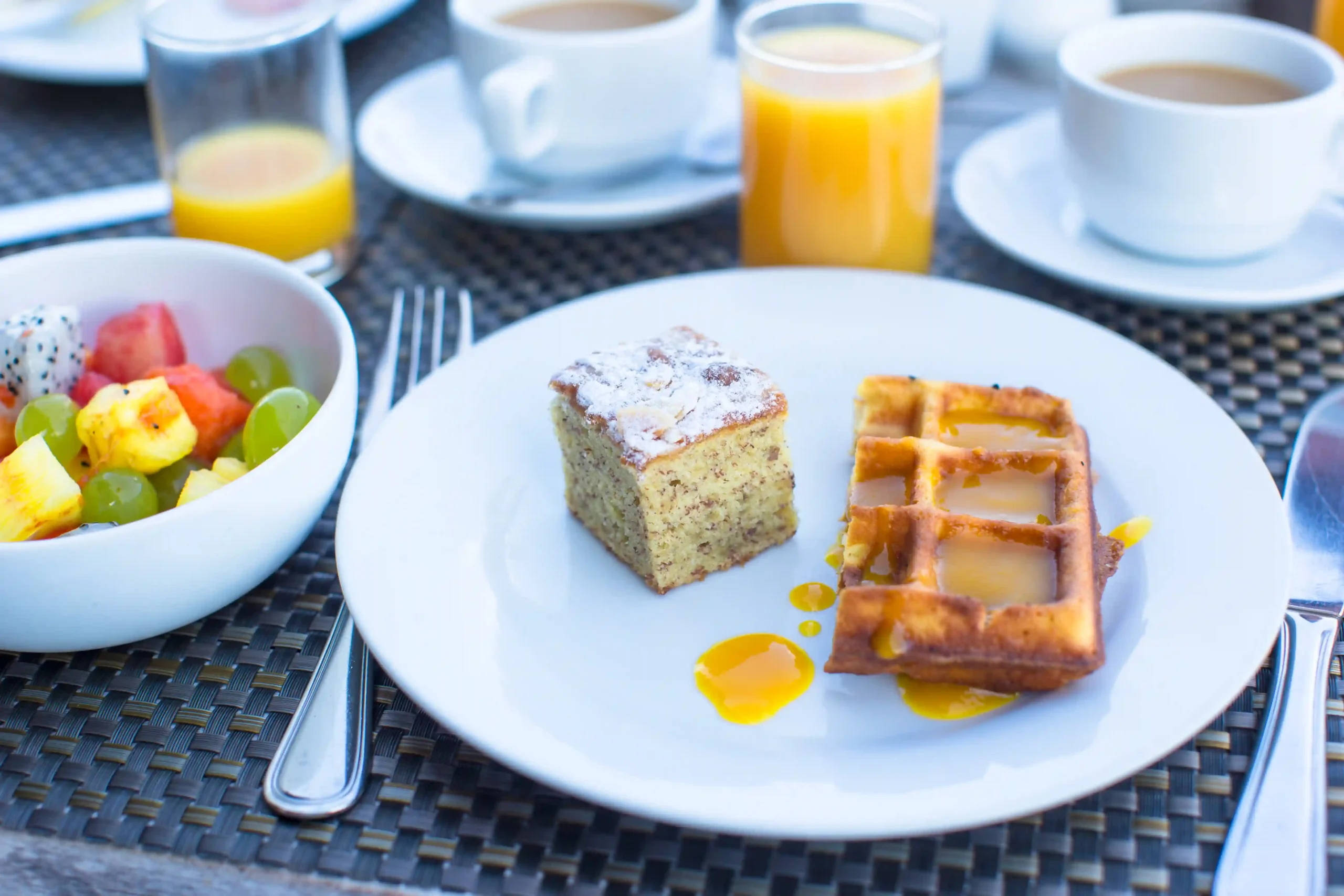 Petit-déjeuner gourmand avec gaufres, gâteau et coupe de fruits frais
