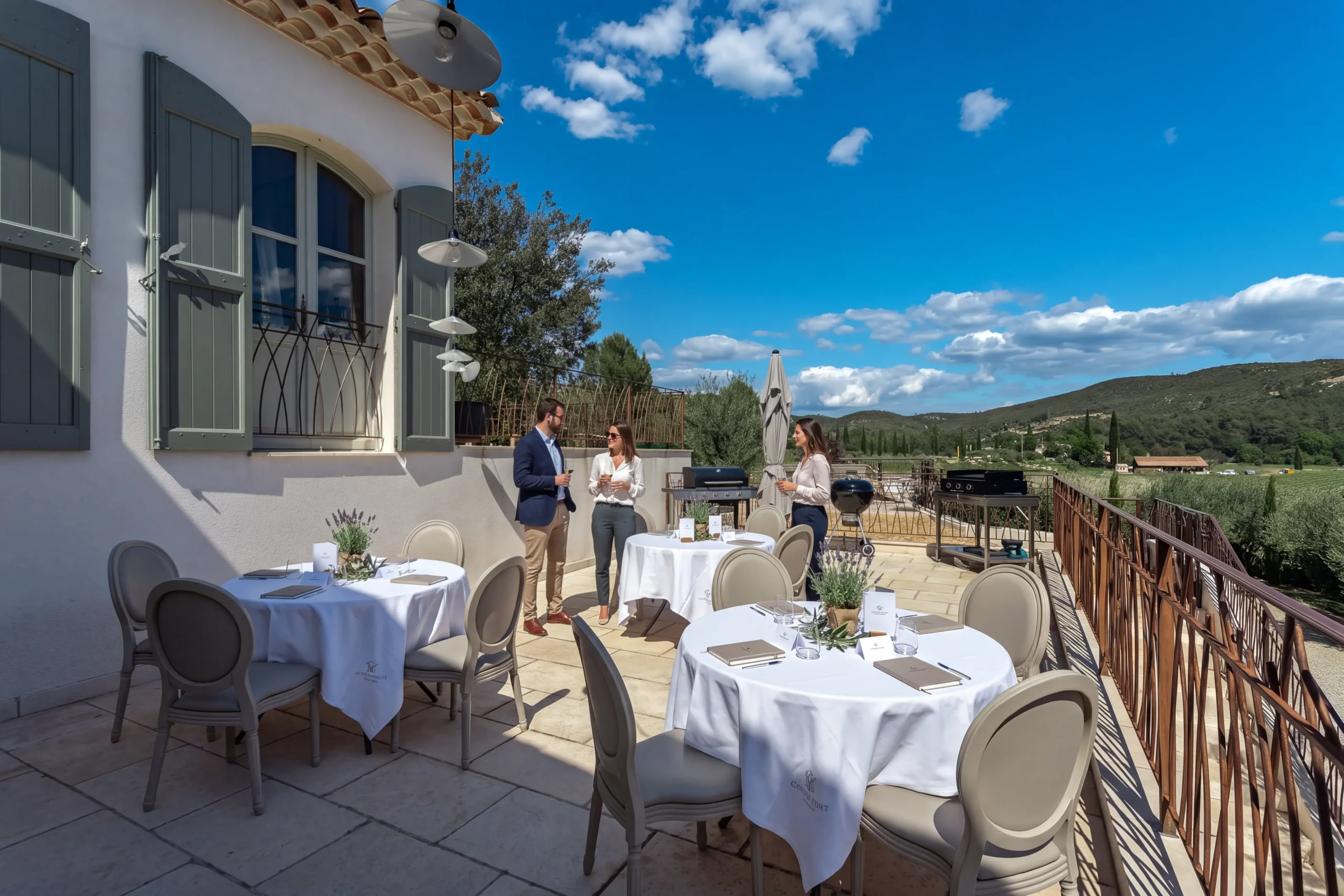 Terrasse en pierre avec table de buffet dressée pour une réception devant la bastide provençale